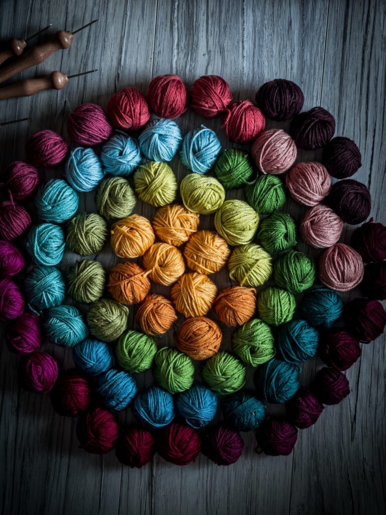 Farverige garnnøgler arrangeret i cirkulært regnbuemønster